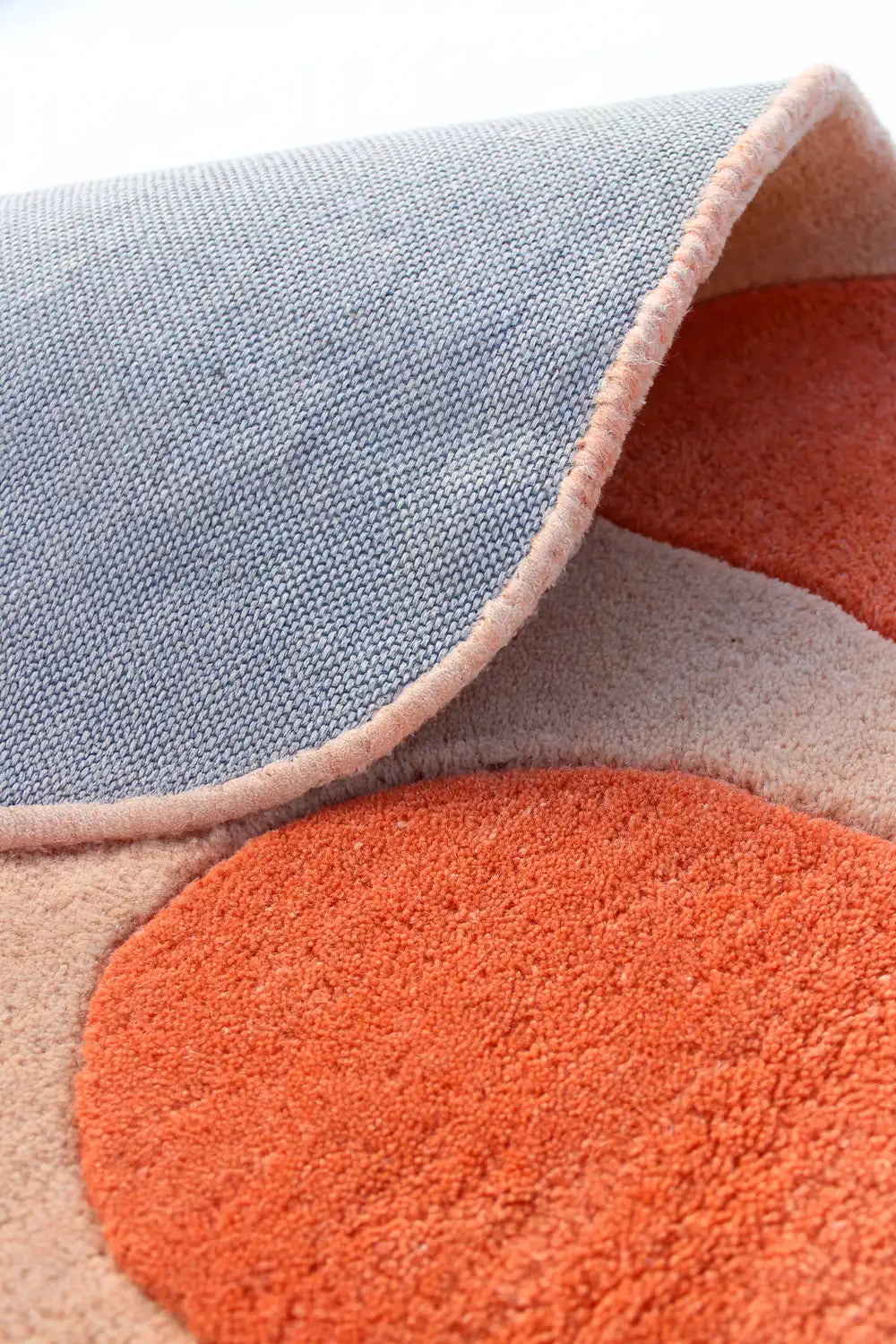 Round wool rug with an abstract floral pattern in orange and beige