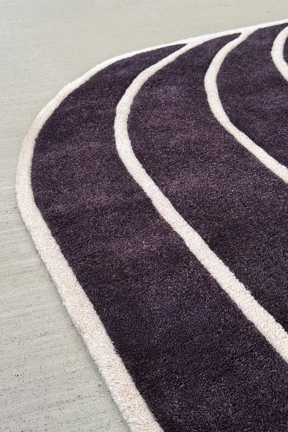 Curved edge of black and cream tufted rug – custom luxury area rug in irregular silhouette

