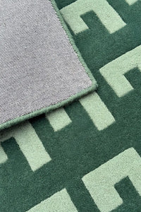 Green geometric rug with soft cotton backing and mint wool pile, shown folded to display structure