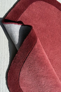 Funky asymmetrical area rug in burgundy and burnt orange, a contemporary novelty rug for colorful living spaces

