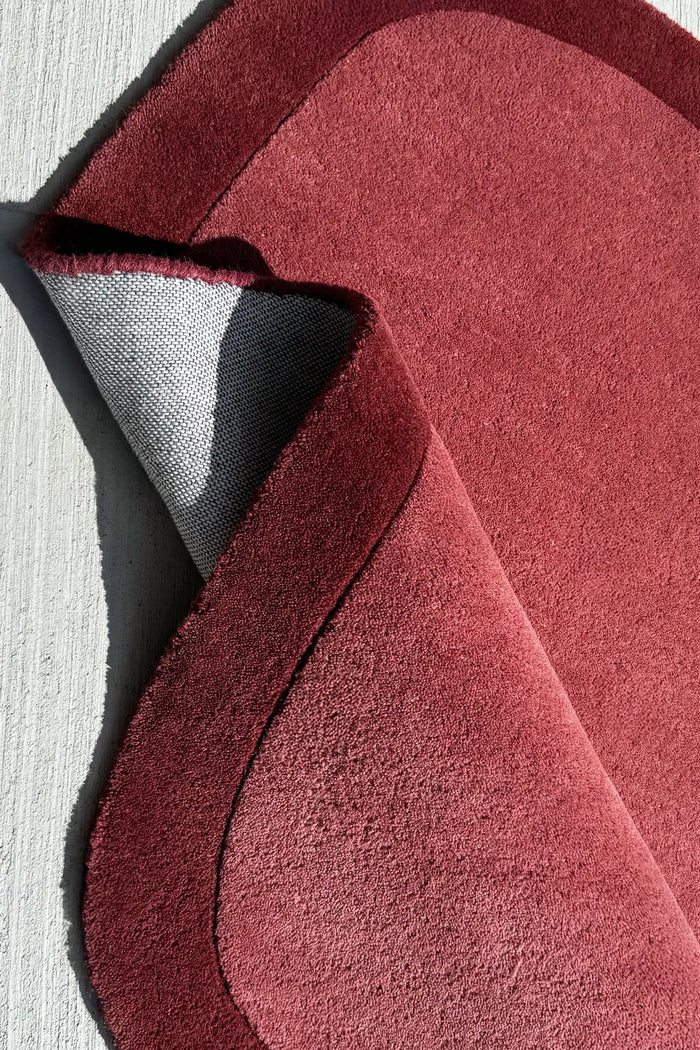 Funky asymmetrical area rug in burgundy and burnt orange, a contemporary novelty rug for colorful living spaces

