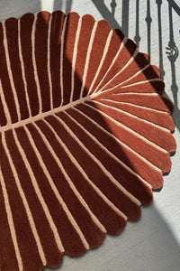 Tropical oval area rug in rich terracotta and cream stripes, with scalloped edges for beach homes or modern interiors

