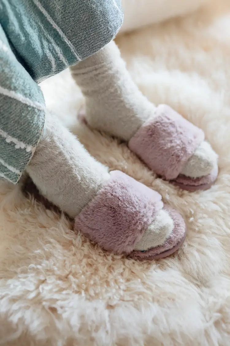 A soft and plush white shag rug providing warmth underfoot, styled with fuzzy slippers for a cozy feel.