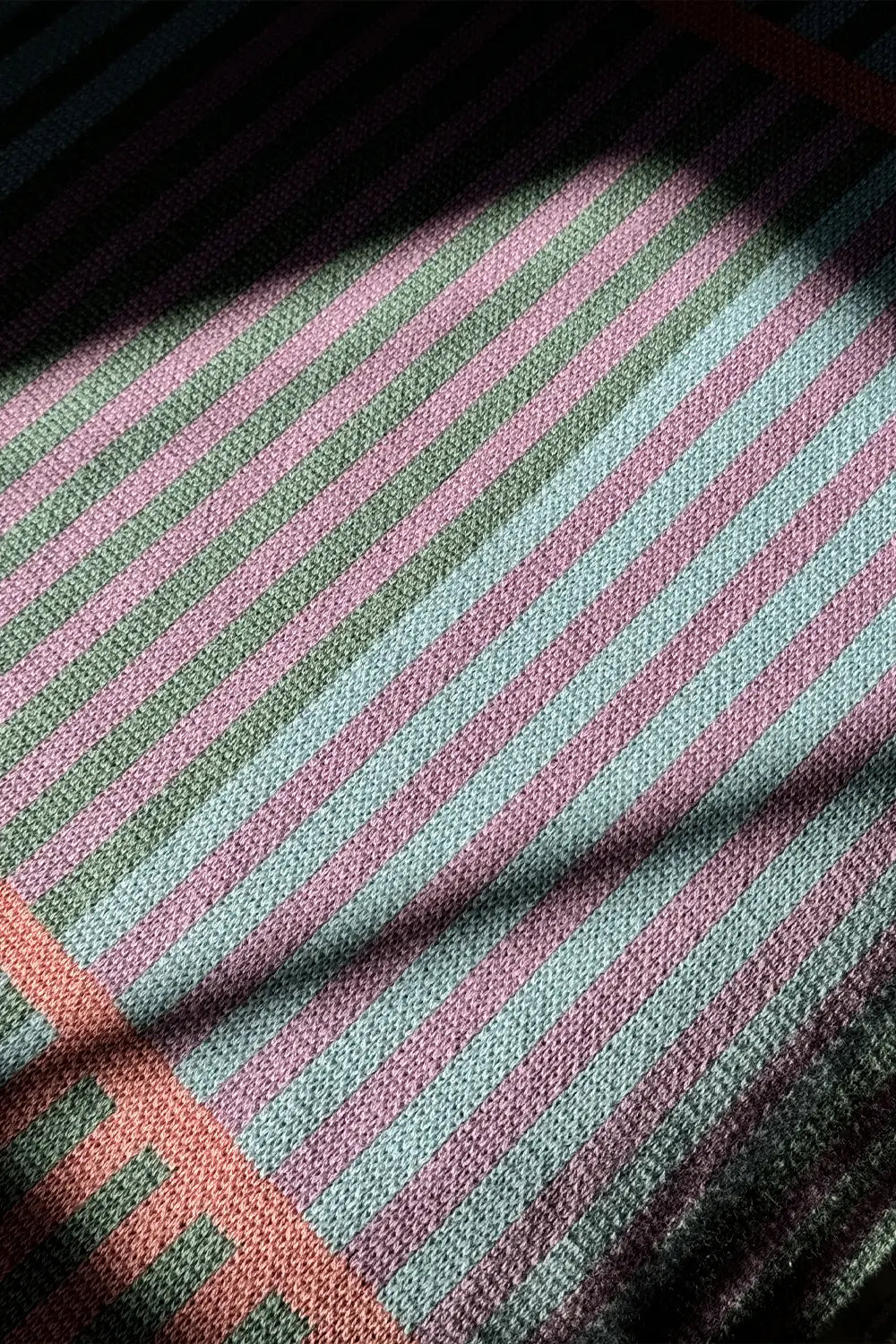 Soft and breathable striped knit blanket in peach, lavender, blue, and green.
