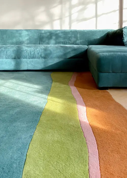 A colorful, modern wool rug featuring bold wavy stripes, adding vibrancy to a spacious, sunlit seating area.