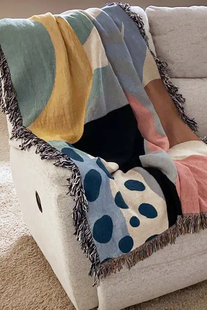 multicolor abstract throw blanket draped over a neutral couch