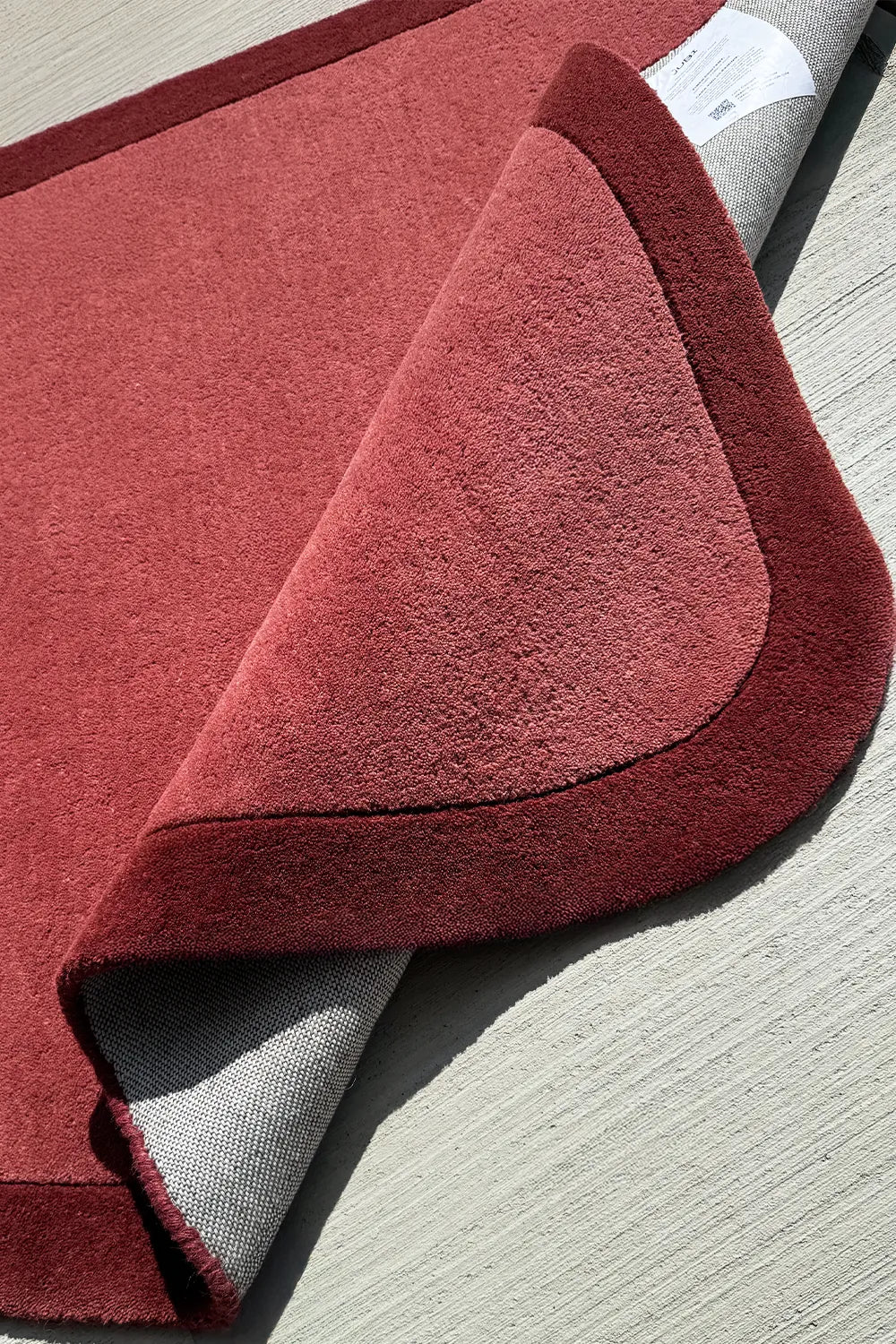 Soft tufted wool corner rug in warm terracotta and burgundy, a unique shaped rug for nursery, entryway, or kids room

