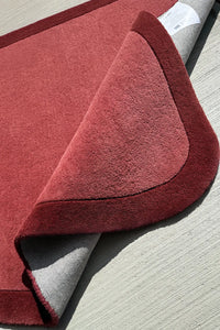 Soft tufted wool corner rug in warm terracotta and burgundy, a unique shaped rug for nursery, entryway, or kids room

