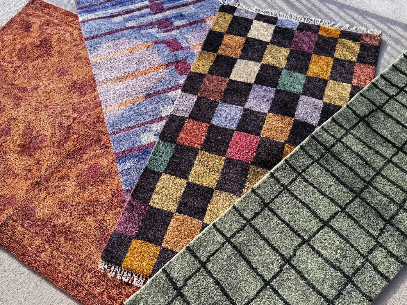 A collection of handmade wool rugs in various patterns, including checkered, abstract, and gridline designs, showcasing Jubi Rugs' craftsmanship and modern aesthetics.