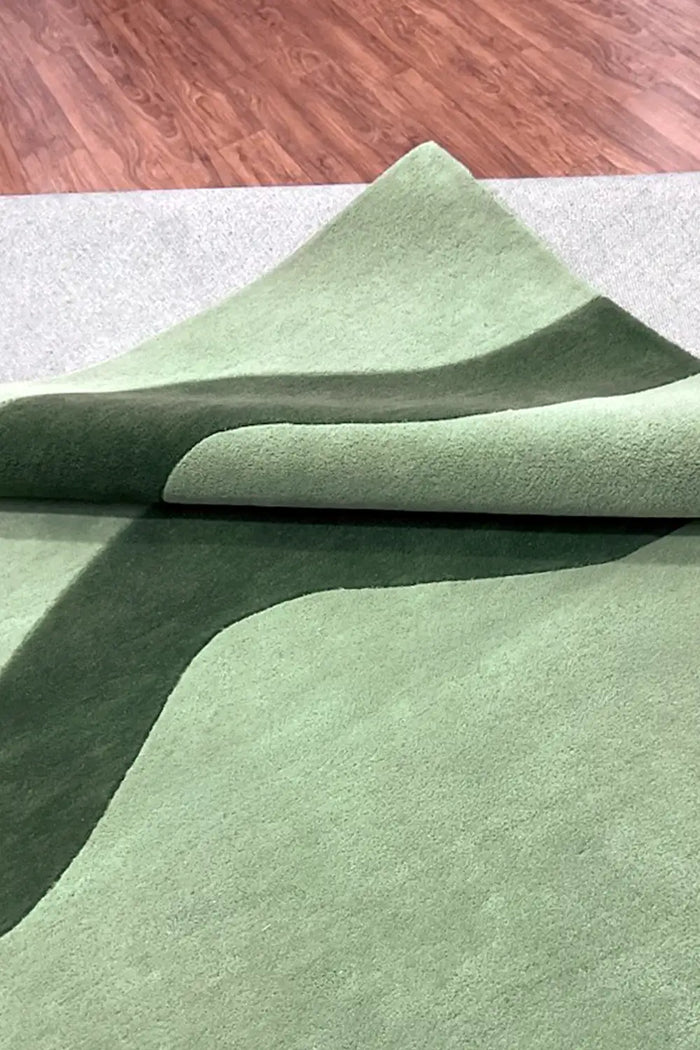 Close-up of sculpted tufted runner rug in sage green with dark wave stripe and plush hand-carved pile