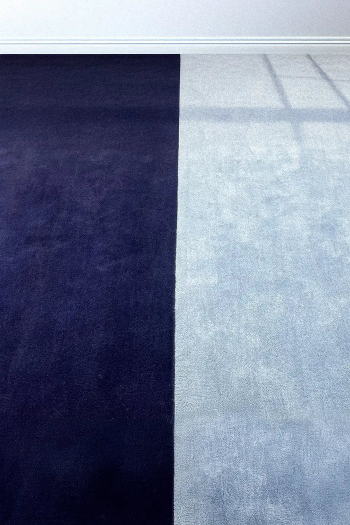 Styled photo of blue and navy block wool area rug showing soft neutral color blocking, ideal for modern coastal or minimal interiors indigo