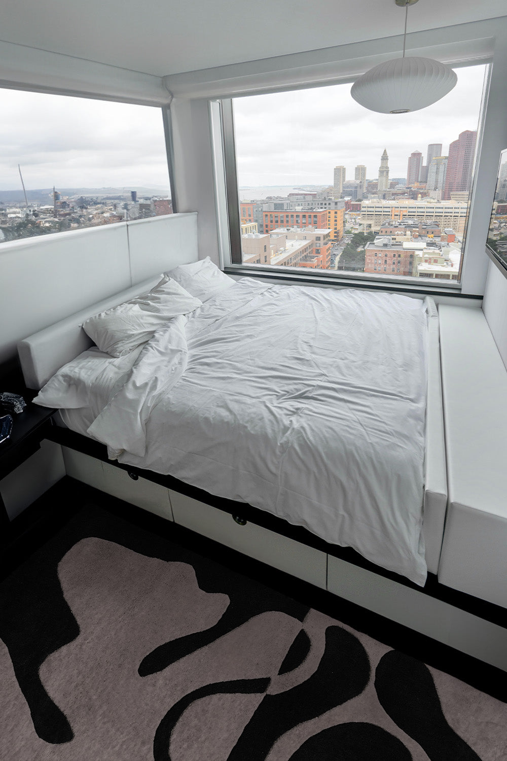 modern bedroom overlooking a city showcasing the organic fusion black and white tufted rug by jubi