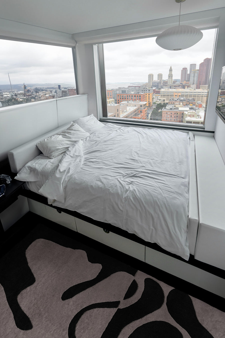 modern bedroom overlooking a city showcasing the organic fusion black and white tufted rug by jubi