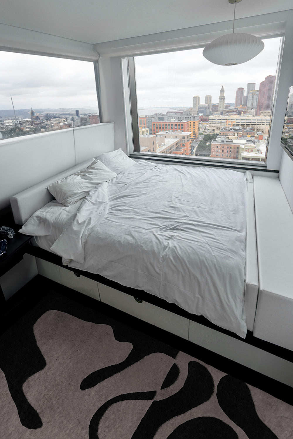 modern bedroom overlooking a city showcasing the organic fusion black and white tufted rug by jubi lifestyle