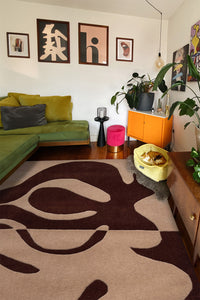 Modern living room with green sofa and brown abstract wool rug centerpiece lifestyle