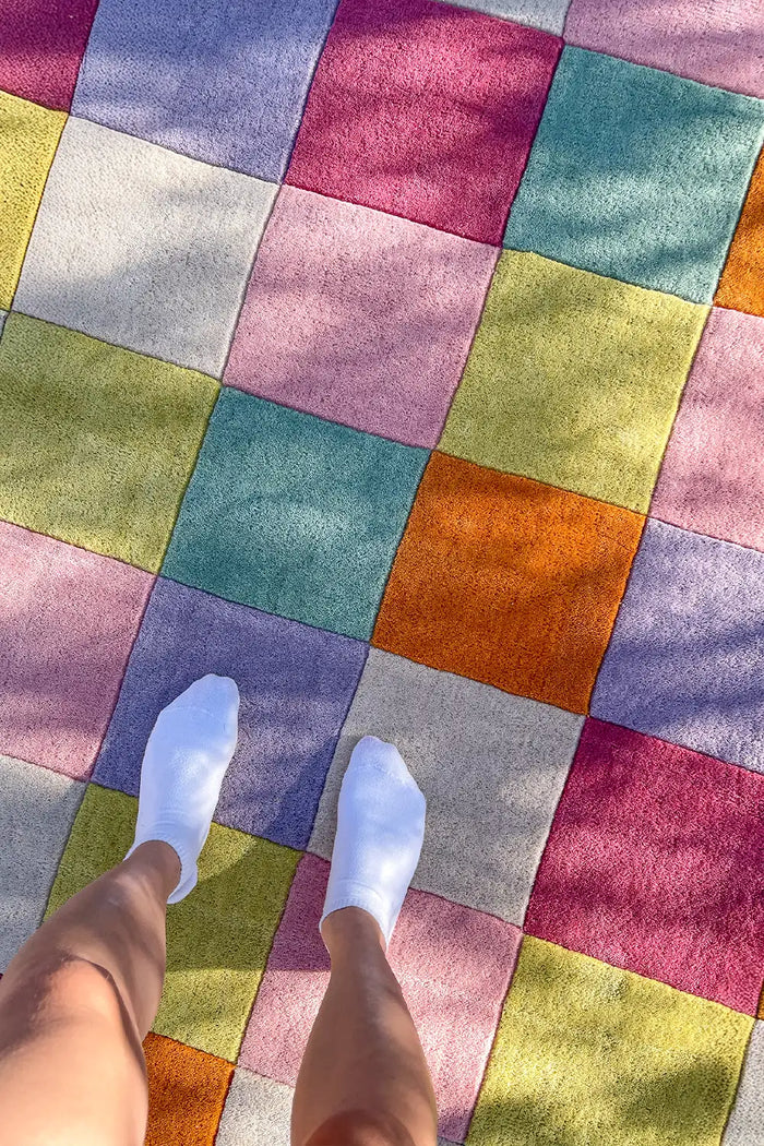Modern colorful checkered wool rug styled in a bright living room lifestyle