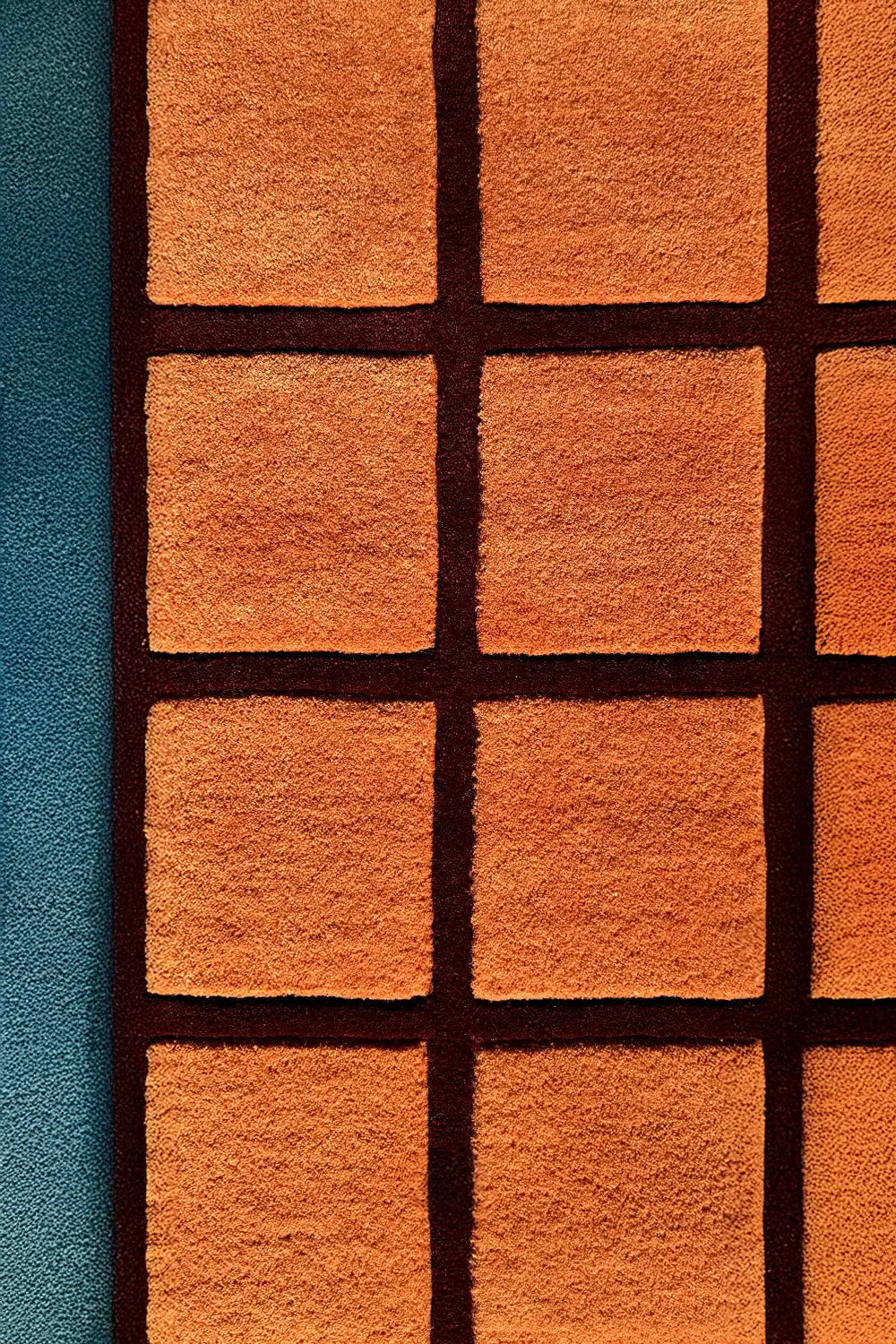 Hand-tufted terracotta wool rug with deep burgundy grid lines and sculpted high-low checkered texture

