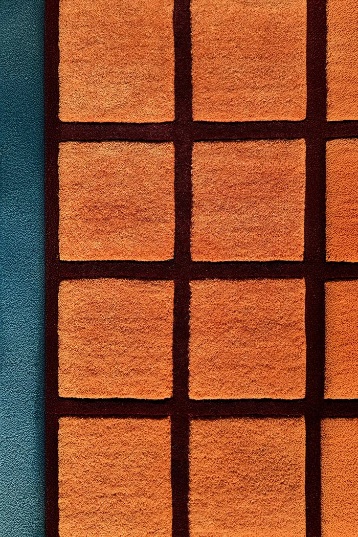 Hand-tufted terracotta wool rug with deep burgundy grid lines and sculpted high-low checkered texture


