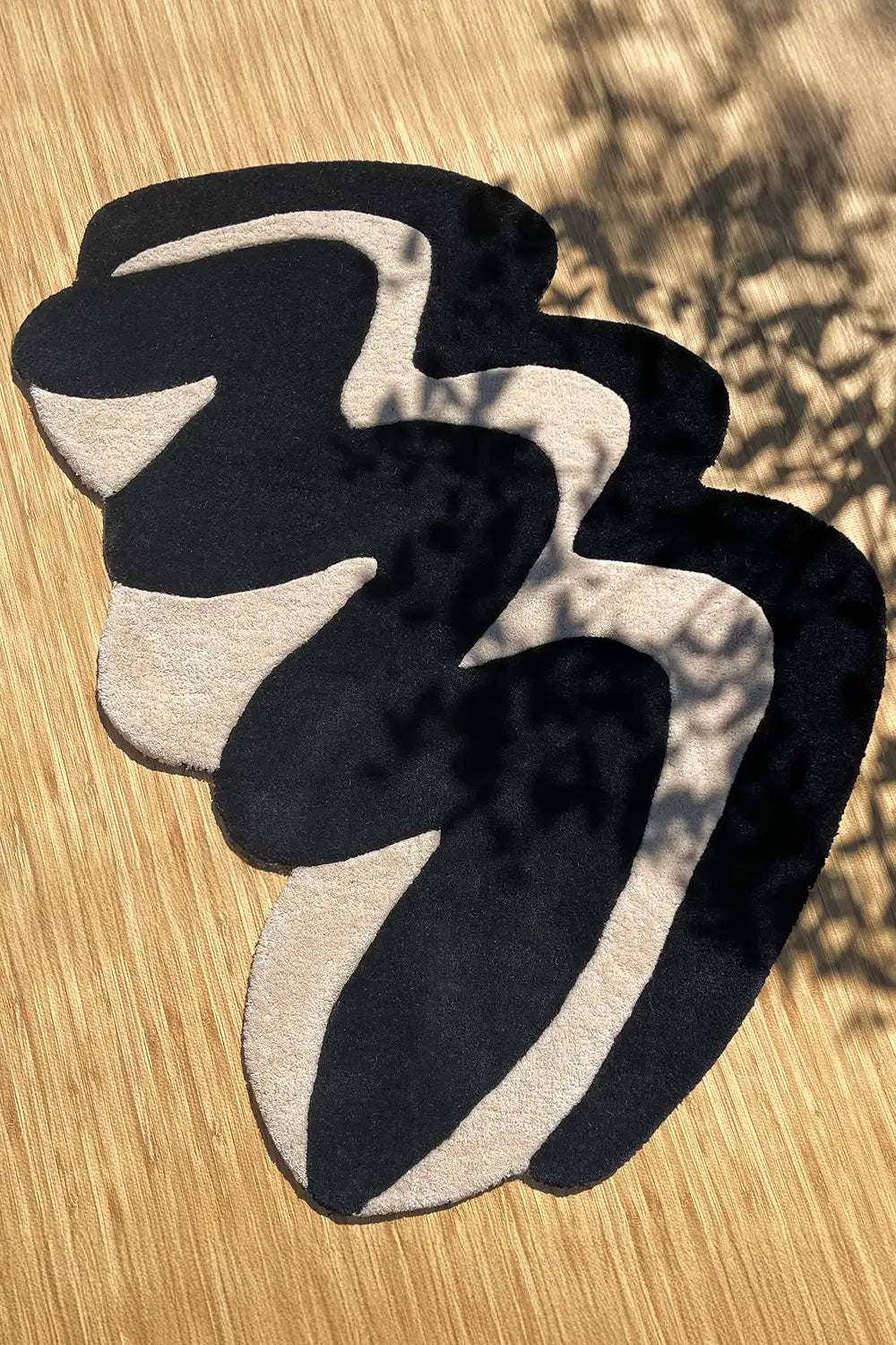 Irregular shaped modern rug with black and ivory curves on wood floor
