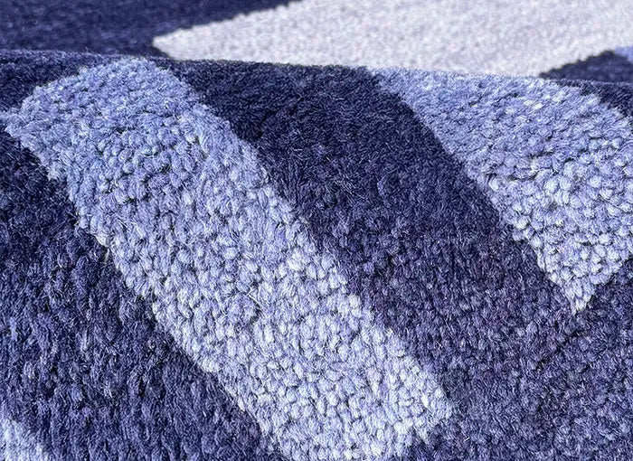 Close-up of a textured blue and navy rug with geometric pattern