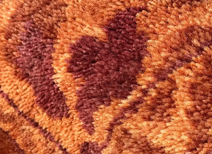 Close-up of a textured orange rug with leaf patterns