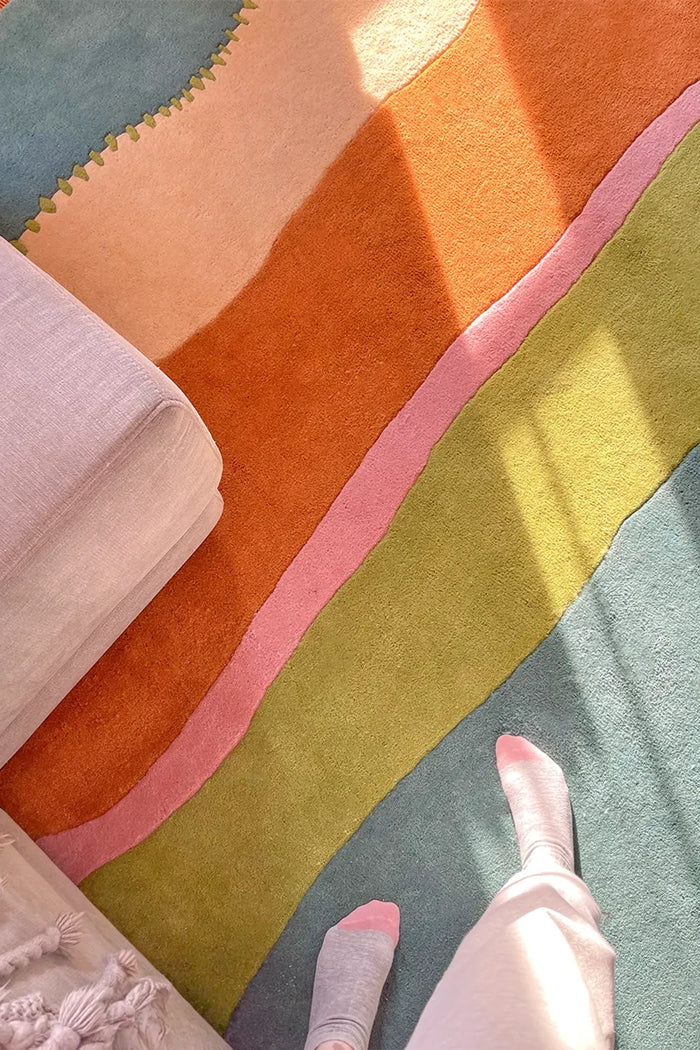 Close-up of colorful boho rug showing orange, pink, and green stripes on teal base
