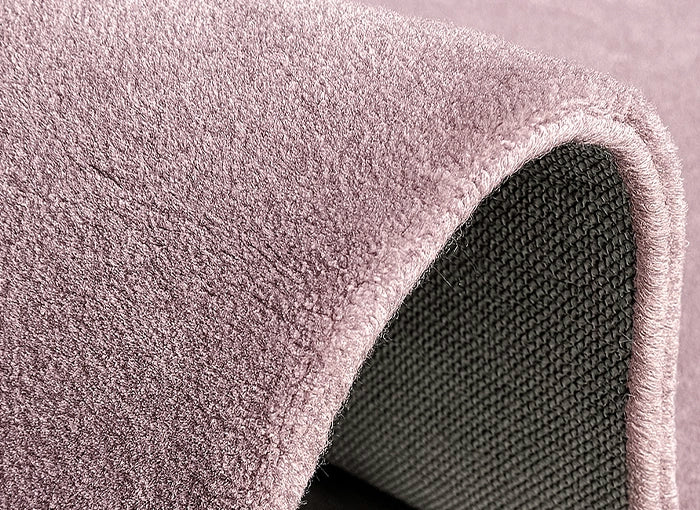 Close-up of a textured pink carpet roll on a light gray background