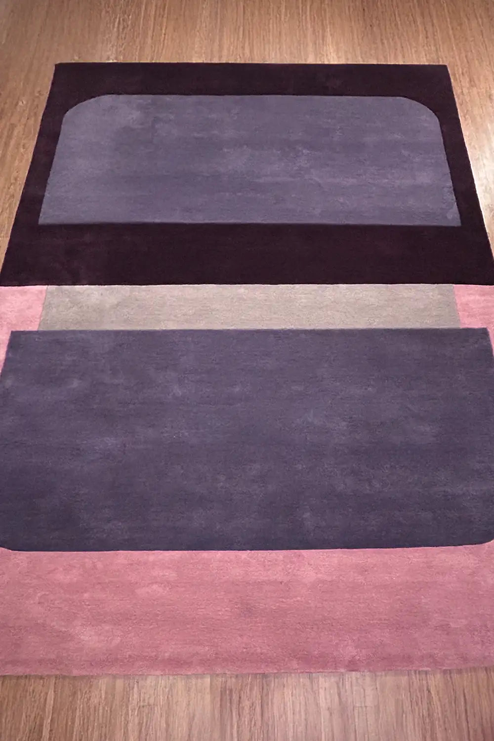 Contemporary pink, plum, and black colorblock wool area rug in 6x9 size, styled on light wood floors