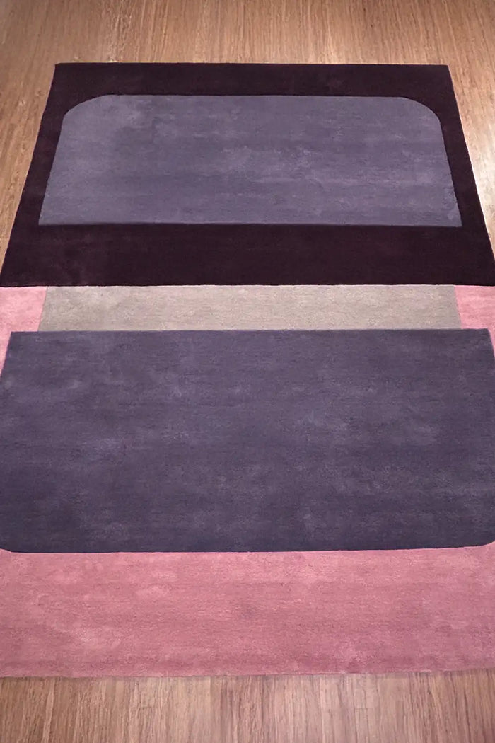 Contemporary pink, plum, and black colorblock wool area rug in 6x9 size, styled on light wood floors