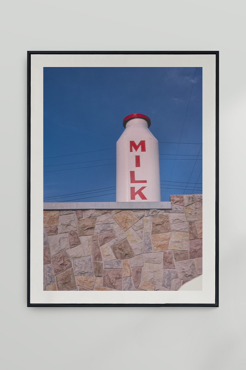 John Margolies' photograph of Milk Bottle roadside attraction against a bright blue sky.