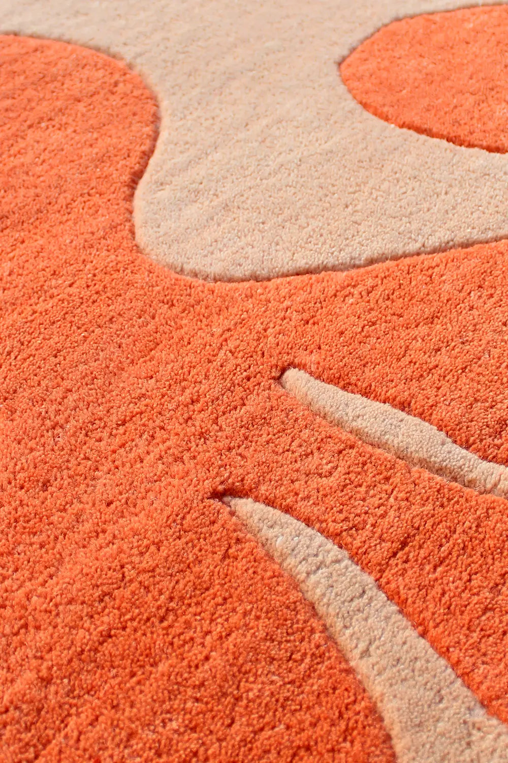 Close-up of the Abstract Floral Tufted Rug's textured wool design, featuring bold orange and neutral tones.