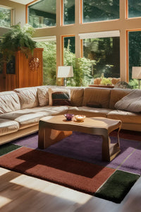 8x10 modern colorblock wool rug styled under mid century tan sectional in sunlit living room with lavender, rust, and green accents