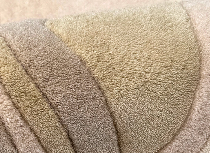 Close-up of a textured rug with a gradient of beige and brown colors.