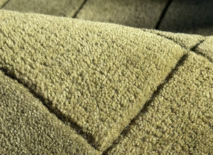 Close-up of a textured green wool rug surface