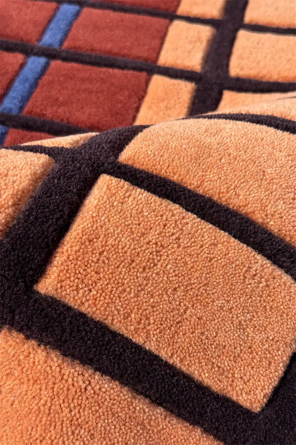 Close-up of a textured square rug with geometric pattern hand-tufted in wool