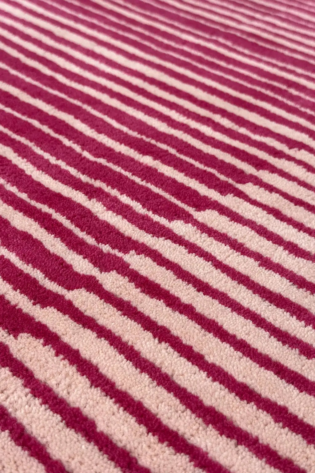 Close-up of a textured rug with magenta and beige stripes