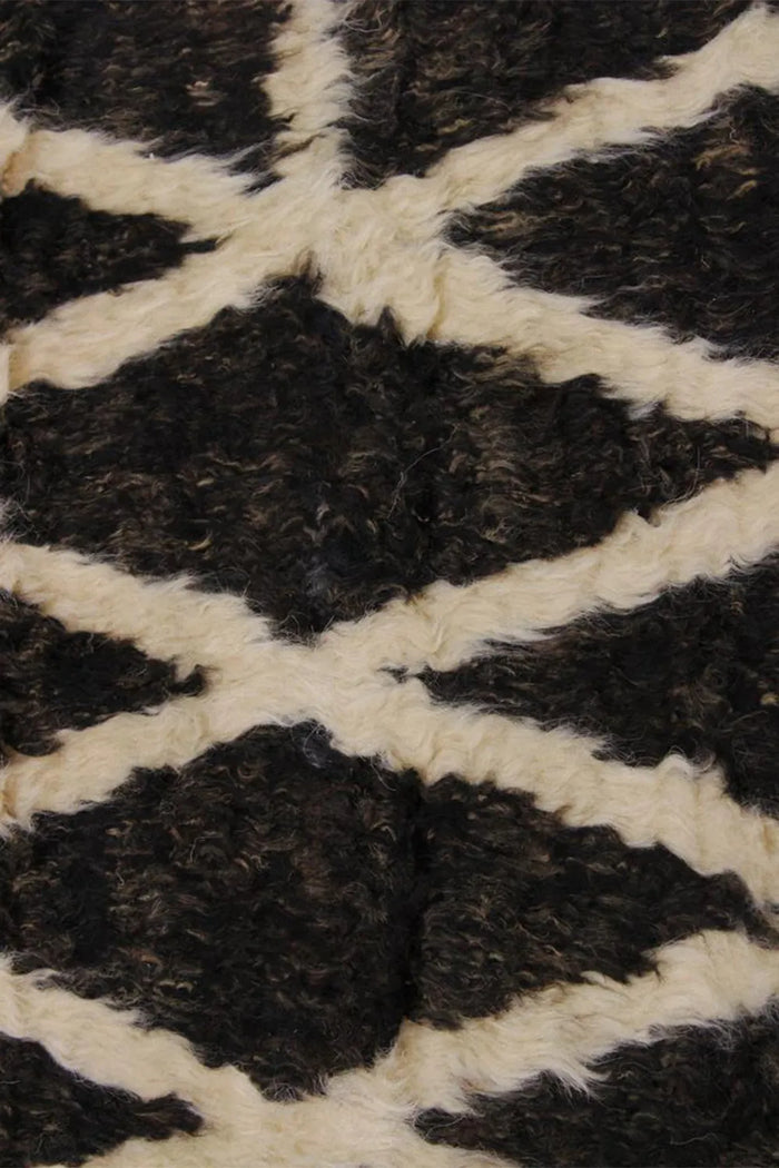 Close-up of plush black shag rug with cream geometric lines, ideal for bohemian living rooms and eclectic modern decor