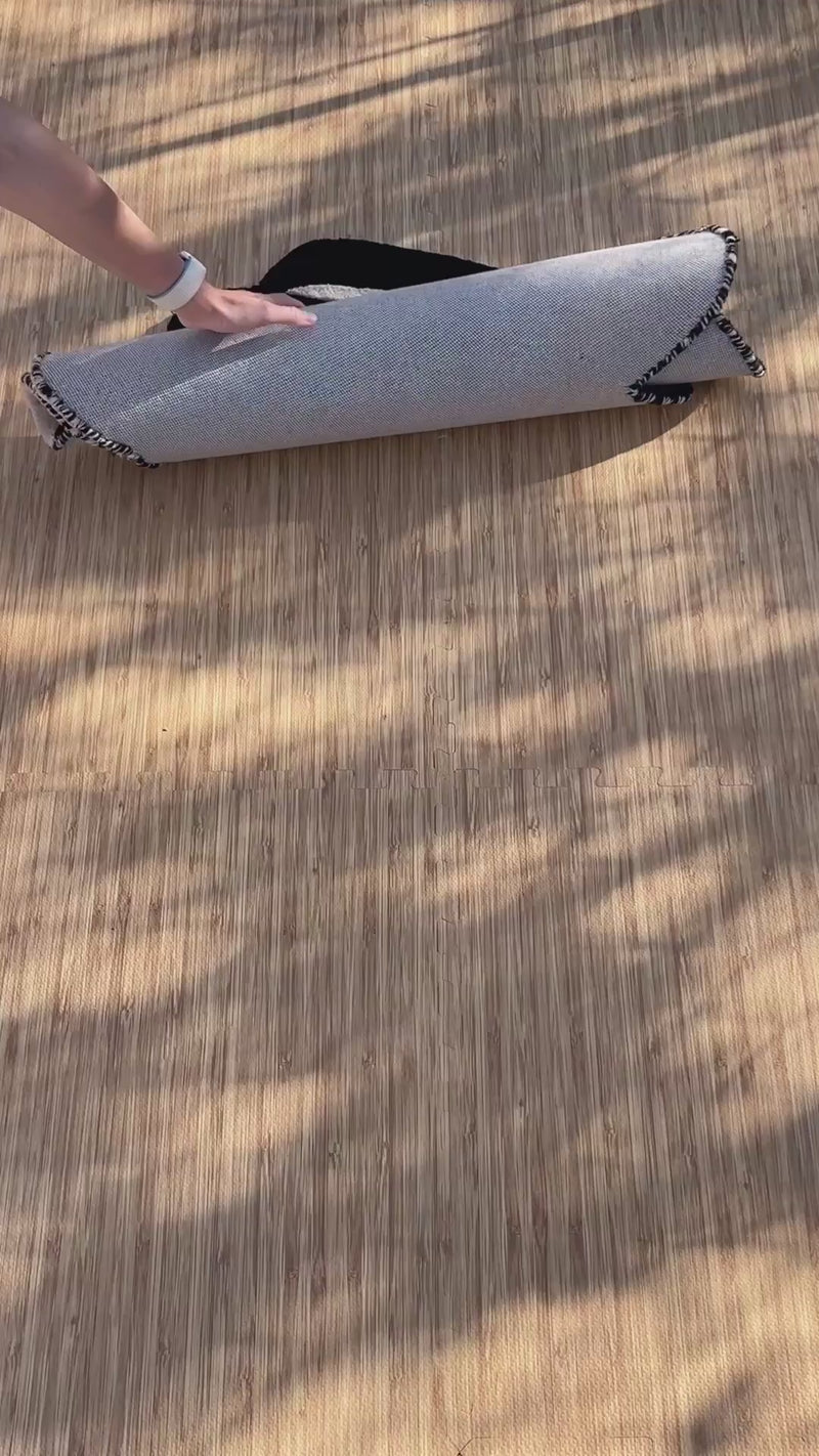 video of a graphic black and cream rug with an irregular shape unrolling in a modern living room


