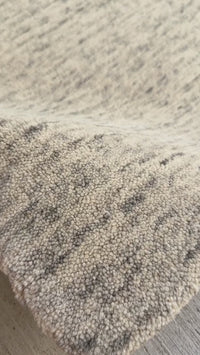 close up of an oat strata hand-tufted wool rug with soft gray strokes
