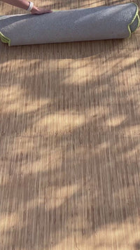 video of a scalloped oval wool rug with ripple stripes in alternating colors of lime green and cream