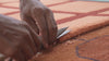 close up video of an artisan's hands as they trim the edges of a hand-tufted rug