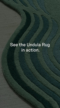 video showcasing texture and unique design of jubi's teal undula irregular shaped rug with hourglass silhouette and grean and blue wavy stripes