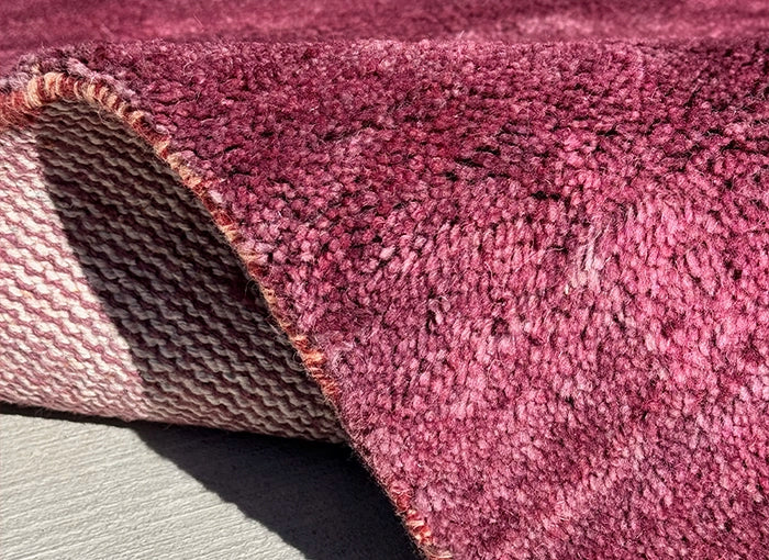 Close-up of a textured purple rug with a slight sheen.