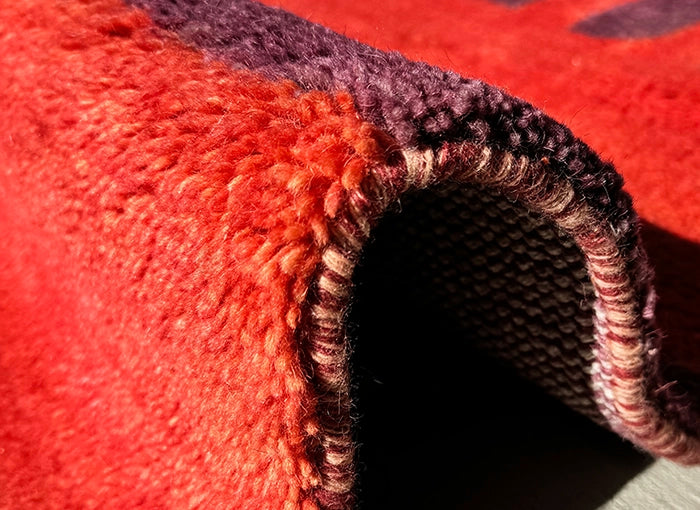 Close-up of a textured red and purple wool rug