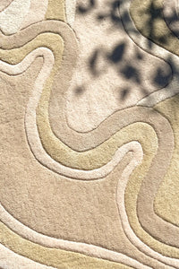 Close-up of high-low sculpted modern wool rug in cream and beige with abstract wavy design