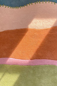 Detail of colorful wool rug with hand-carved flowing lines in terracotta, pink, and green
