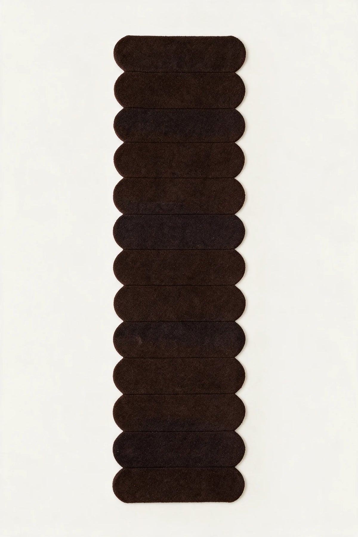 a detail of a temple steps hand-tufted wool runner in brown and black