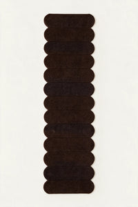 a detail of a temple steps hand-tufted wool runner in brown and black