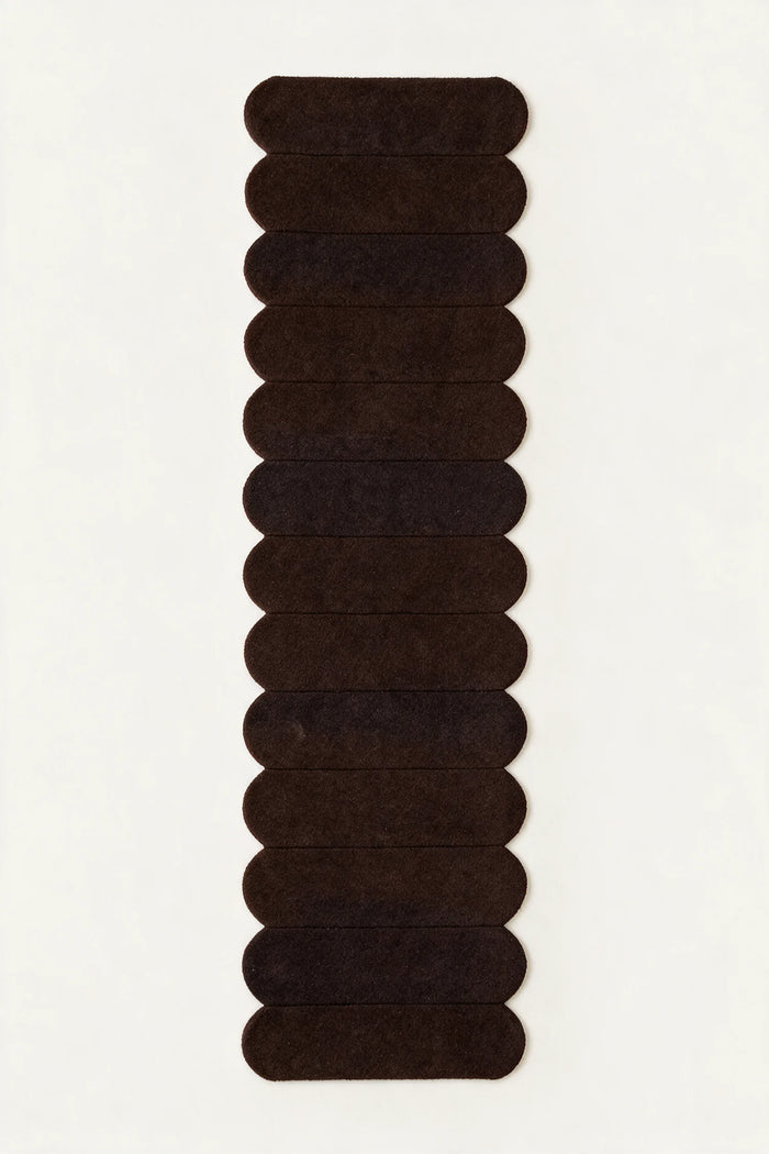 a detail of a temple steps hand-tufted wool runner in brown and black