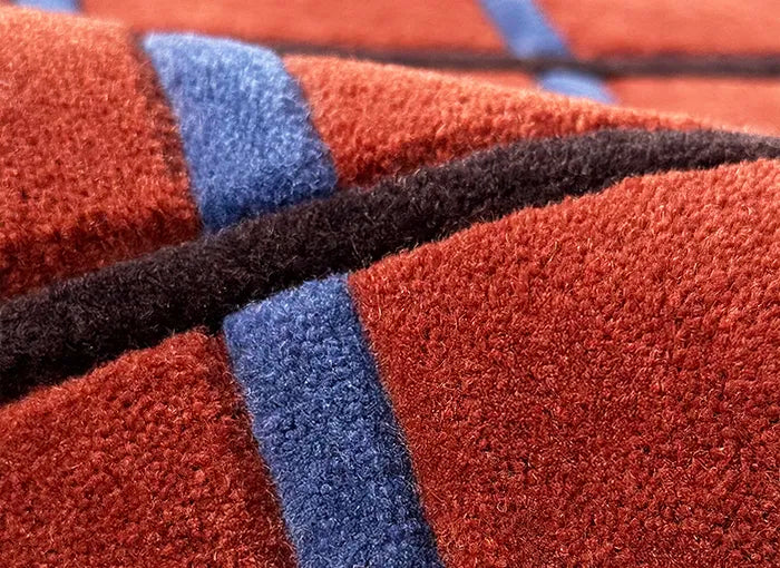 Close-up of a textured wool rug with brown, blue, and black colors.